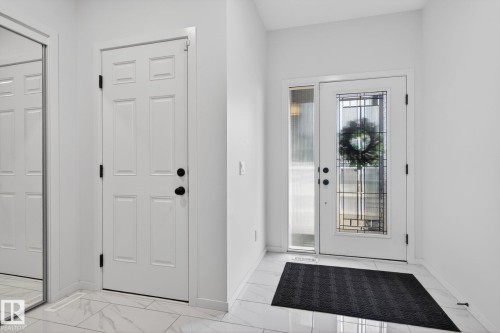 Entryway featuring a white paneled door with black hardware, an additional white door with decorative glass inserts, and a sidelight - 7011 177 Avenue, Edmonton, AB - Indoor Photo Showing Other Room
