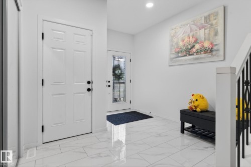 Entryway featuring white six-panel interior door, glass-paneled exterior door, and large format white tile flooring - 7011 177 Avenue, Edmonton, AB - Indoor Photo Showing Other Room
