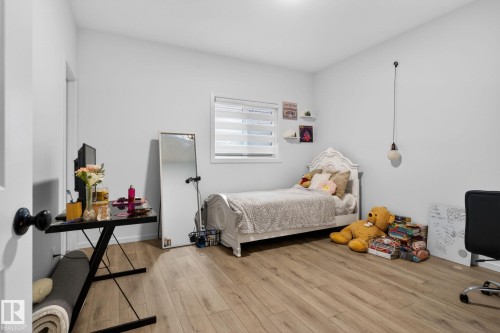 Bright room featuring wood-finish flooring, a single window with blinds, and white painted walls - 7011 177 Avenue, Edmonton, AB - Indoor Photo Showing Bedroom