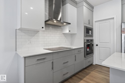 Modern kitchen featuring white subway tile backsplash, white countertops, and wood-finish flooring - 7011 177 Avenue, Edmonton, AB - Indoor Photo Showing Kitchen With Upgraded Kitchen
