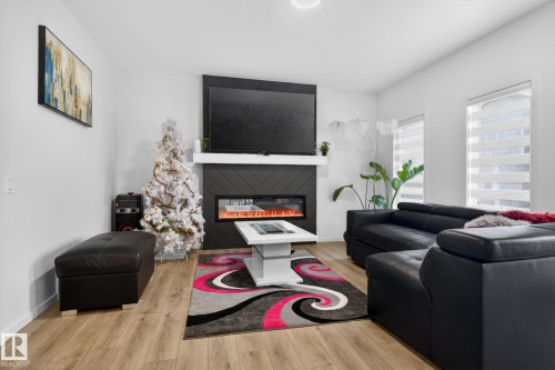 Contemporary living area with wood-finish flooring and white wall finishes - 7011 177 Avenue, Edmonton, AB - Indoor Photo Showing Living Room With Fireplace