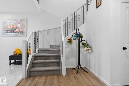 Carpeted staircase with white risers and black metal spindles - 7011 177 Avenue, Edmonton, AB - Indoor Photo Showing Other Room