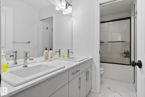 Double vanity with integrated rectangular sinks, chrome faucets, and light-toned countertops - 7011 177 Avenue, Edmonton, AB - Indoor Photo Showing Bathroom