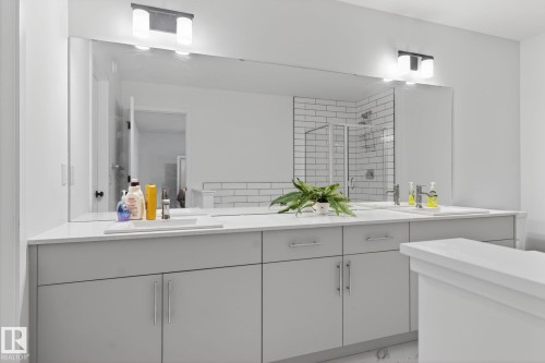 Dual vanity with undermount sinks, light-toned countertops, and grey cabinetry - 7011 177 Avenue, Edmonton, AB - Indoor Photo Showing Bathroom