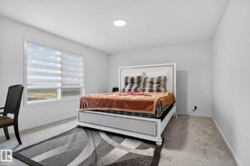 Bright room featuring a large window with horizontal blinds, neutral wall paint, recessed lighting, and carpet flooring - 7011 177 Avenue, Edmonton, AB - Indoor Photo Showing Bedroom