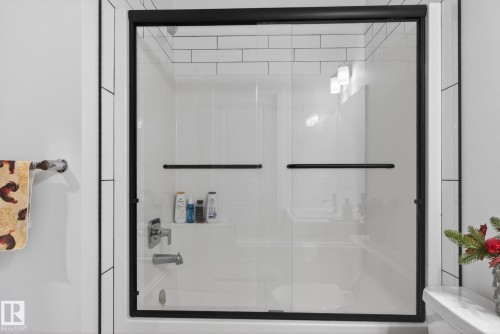 White subway tile surround with black grout and glass shower enclosure featuring matte black framing - 7011 177 Avenue, Edmonton, AB - Indoor Photo Showing Bathroom
