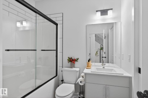 Contemporary bathroom featuring a tub-shower combination with subway tile surround and black-framed glass doors - 7011 177 Avenue, Edmonton, AB - Indoor Photo Showing Bathroom