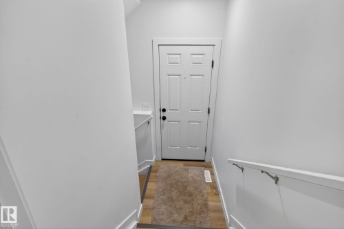 White paneled door with matte black hardware, set against light-toned wood-finish flooring - 7011 177 Avenue, Edmonton, AB - Indoor Photo Showing Other Room