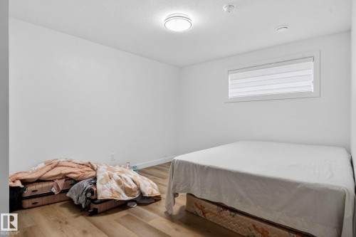 Bedroom featuring wood-finish flooring, a contemporary ceiling light fixture, and a window with horizontal blinds - 7011 177 Avenue, Edmonton, AB - Indoor Photo Showing Bedroom