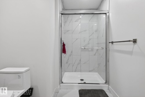 Walk-in shower featuring a frameless glass enclosure and large format marble-look tile - 7011 177 Avenue, Edmonton, AB - Indoor Photo Showing Bathroom