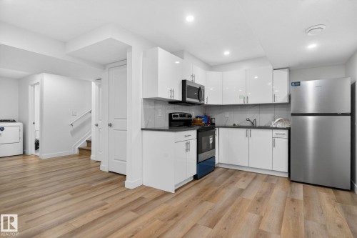 Contemporary kitchen featuring white cabinetry, dark countertops, and stainless steel appliances - 7011 177 Avenue, Edmonton, AB - Indoor Photo Showing Kitchen