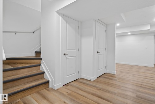 Lower-level space featuring wood-finish flooring, recessed lighting, and two panel doors with satin nickel hardware - 7011 177 Avenue, Edmonton, AB - Indoor Photo Showing Other Room