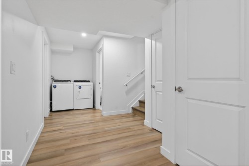 Dedicated laundry area with light wood-finish flooring, white walls, and bright overhead lighting - 7011 177 Avenue, Edmonton, AB - Indoor Photo Showing Laundry Room