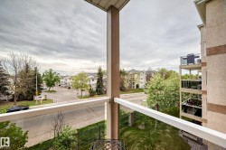 Private balcony featuring glass railings, a painted metal column, and an exterior light fixture - 