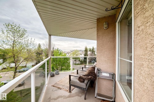 Private balcony featuring a textured stucco exterior, white soffit, and clear glass panel railings - 331 9704 174 Street, Edmonton, AB - Outdoor With Exterior