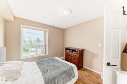 Bedroom featuring a large window, neutral wall paint, wood-finish flooring, and a flush-mount ceiling light - 