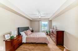 Bedroom featuring wood-finish flooring, a tray ceiling, and a ceiling fan - 