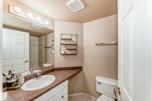 Bathroom featuring a white vanity with an integrated sink, a brown countertop, and a large wall mirror - 331 9704 174 Street, Edmonton, AB - Indoor Photo Showing Bathroom