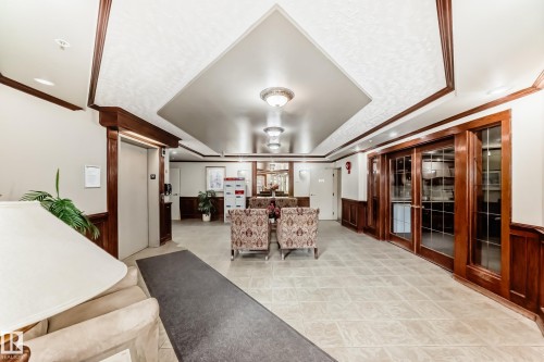 Spacious lobby featuring tile flooring, dark wood wainscoting, and an elevator access point - 331 9704 174 Street, Edmonton, AB - Indoor Photo Showing Other Room