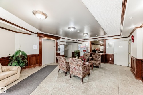Lobby area featuring wood-paneled wainscoting, decorative crown molding, and tiled flooring - 331 9704 174 Street, Edmonton, AB - Indoor