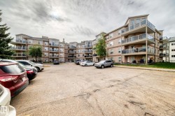 Multi-story building featuring tan siding and multiple balconies with glass railings - 