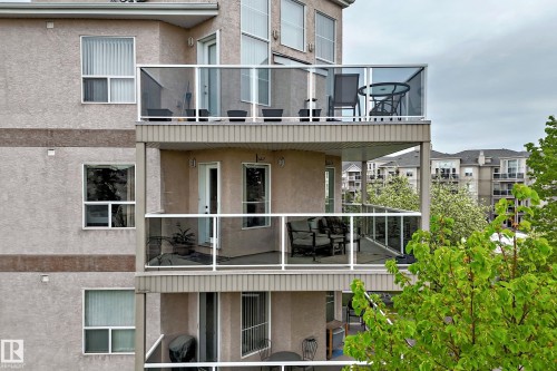 Multi-level balconies featuring glass panel railings, textured stucco exterior, and white frame windows - 331 9704 174 Street, Edmonton, AB - Outdoor With Exterior
