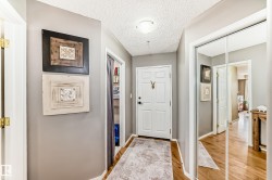 Foyer featuring wood-finish flooring, a white paneled entry door, and mirrored sliding closet doors - 