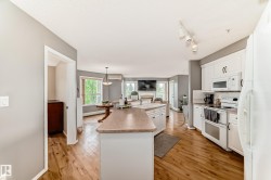 Kitchen featuring white cabinetry, white appliances, and a central island with a breakfast bar - 