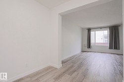 Open concept area featuring light wood-finish flooring, white walls, and a large window - 
