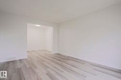 Spacious interior featuring light wood-finish flooring, white baseboards, and neutral wall tones throughout - 