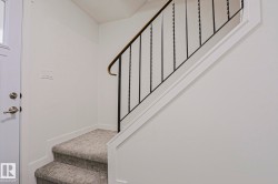 Carpeted staircase featuring wrought iron balusters and a brass-tone handrail - 