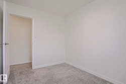 Neutral-toned room featuring a new door with brushed nickel hardware, light gray patterned carpeting, and crisp white baseboards - 