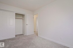 Room featuring neutral-toned walls, textured gray carpet flooring, and white baseboards - 