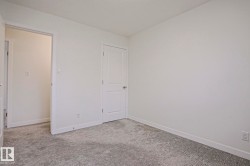 Spacious room featuring light gray patterned carpeting, crisp white wall paint, and white trim - 