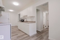 Kitchen featuring white cabinetry, gray countertop, white subway tile backsplash, and wood-finish flooring - 