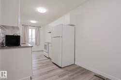 Kitchen featuring light wood-finish flooring, white cabinetry, and white appliances - 