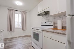 Kitchen featuring white cabinetry, gray patterned countertops, and a white subway tile backsplash - 