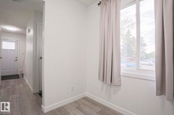 Interior space featuring light grey wood-finish flooring, white walls, and a large window with white trim - 