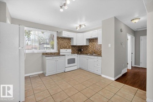 Kitchen featuring white cabinetry, tile backsplash, laminate countertops, and white appliances - 4630 114 Avenue, Edmonton, AB - Indoor Photo Showing Kitchen