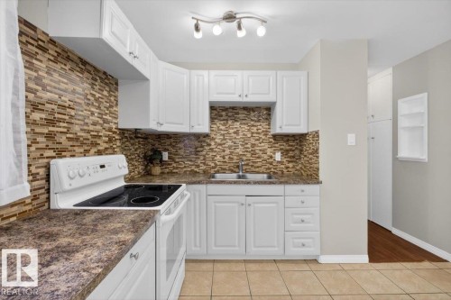 Kitchen featuring white cabinetry, a mosaic tile backsplash, a built-in range, and a double basin sink - 4630 114 Avenue, Edmonton, AB - Indoor Photo Showing Kitchen With Double Sink