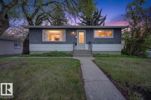 Single-story property featuring a stucco and horizontal siding exterior, a concrete walkway, and mature trees - 4630 114 Avenue, Edmonton, AB - Outdoor