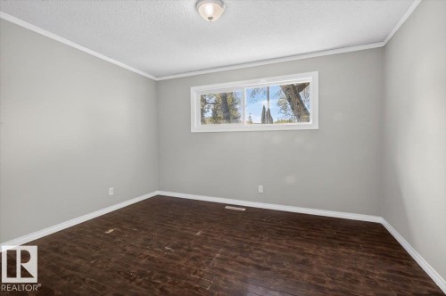 Spacious room featuring wood-finish flooring, light gray wall paint, and white trim - 4630 114 Avenue, Edmonton, AB - Indoor Photo Showing Other Room