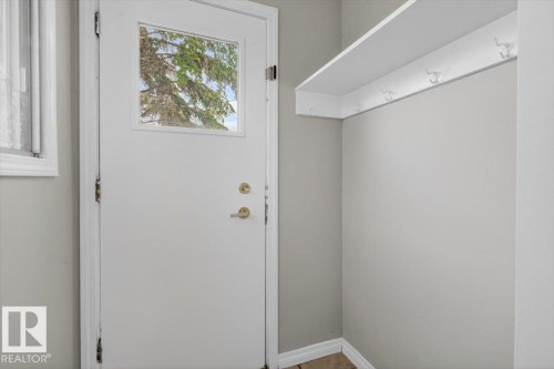 Entryway featuring a white door with an upper window, coordinating white trim, light gray painted walls, a built-in white shelf, and multiple coat hooks - 4630 114 Avenue, Edmonton, AB - Indoor Photo Showing Other Room