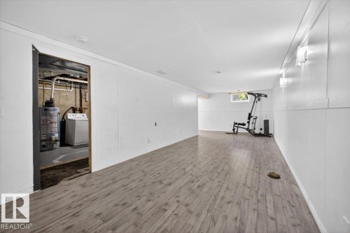 Finished lower level featuring wood-finish flooring, white paneling, multiple wall sconces, and a recessed window - 4630 114 Avenue, Edmonton, AB - Indoor Photo Showing Other Room