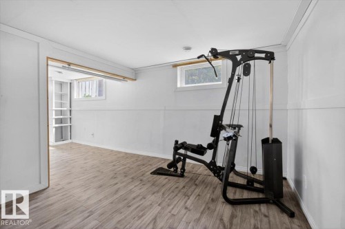 Spacious room with wood-finish flooring, white paneled walls, and two visible windows - 4630 114 Avenue, Edmonton, AB - Indoor Photo Showing Gym Room