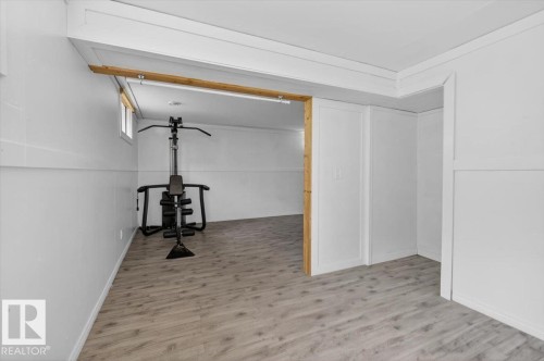 Finished basement area featuring plank-style flooring, white paneling, white walls, and a small window for natural light - 4630 114 Avenue, Edmonton, AB - Indoor