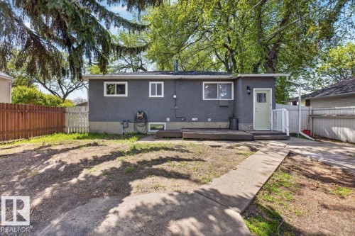 Rear exterior featuring gray stucco siding, white-framed windows, and a light green entry door with a white railing - 4630 114 Avenue, Edmonton, AB - Outdoor