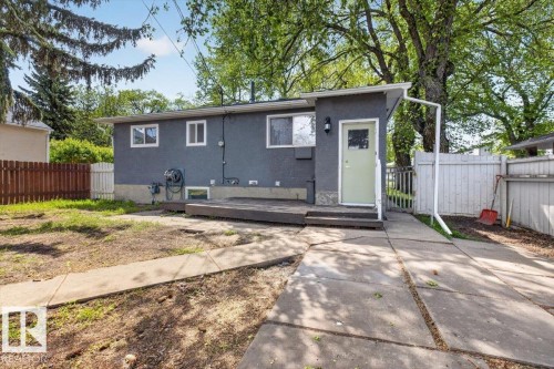 Rear exterior featuring a grey stucco finish, light green entry door, and multi-pane windows - 4630 114 Avenue, Edmonton, AB - Outdoor
