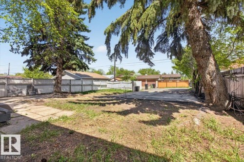 Expansive backyard featuring mature trees, a concrete patio area, and perimeter fencing - 4630 114 Avenue, Edmonton, AB - Outdoor