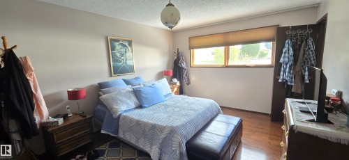 Bedroom featuring wood-finish flooring, a double window with roller blinds, and a ceiling-mounted globe light fixture - 5113 45 B Avenue, Vegreville, AB - Indoor Photo Showing Bedroom